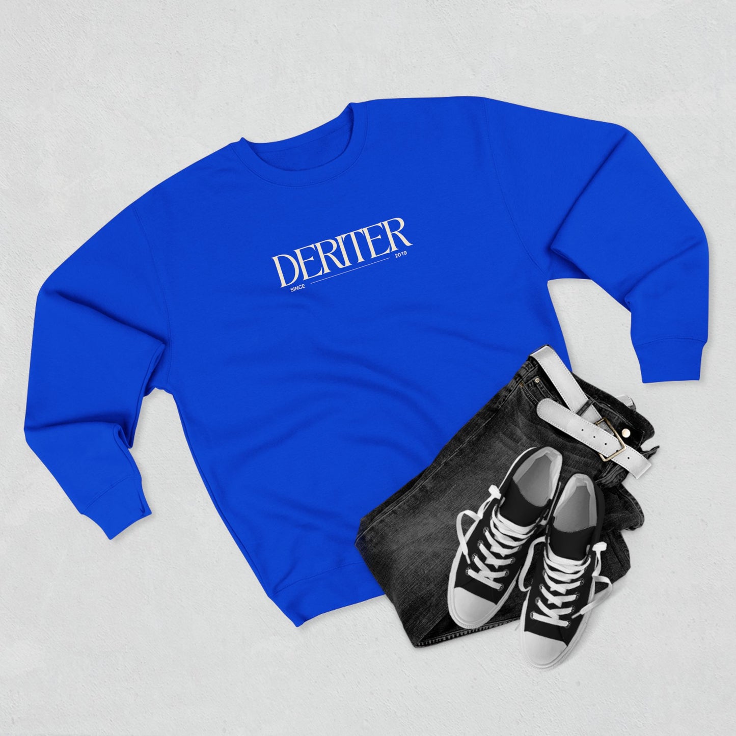 Blue sweatshirt with 'DERITER' branding, black pouch, and black sneakers on a light gray background